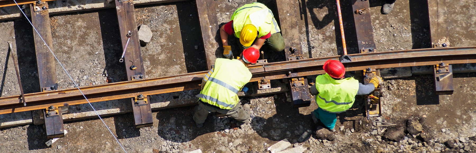 Three men in yellow safety vests working on a railroad 