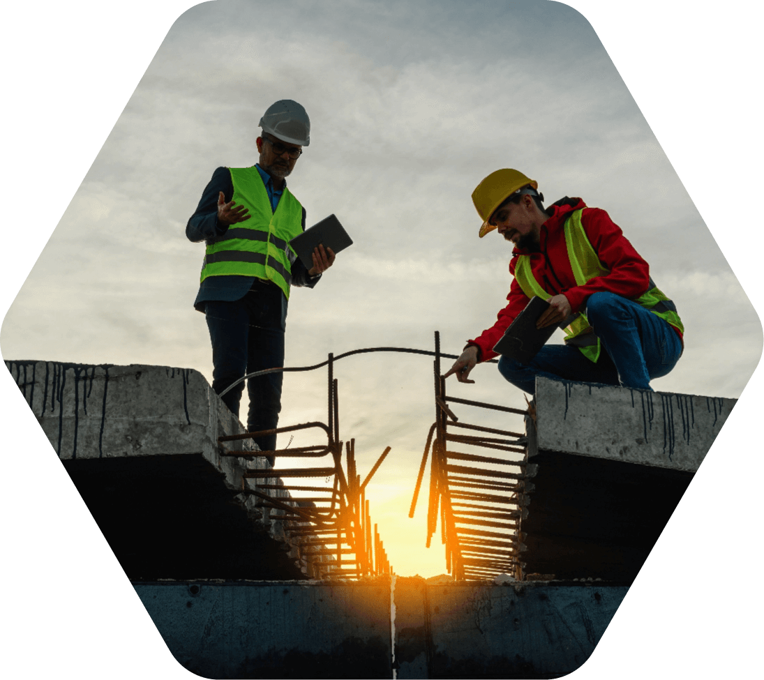 Two men in safety vests at a construction site as the sun sets