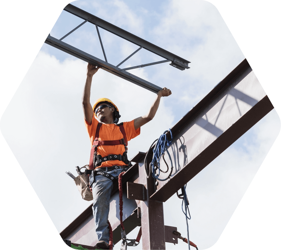 Worker in orange shirt assembling parts of a steel bridge