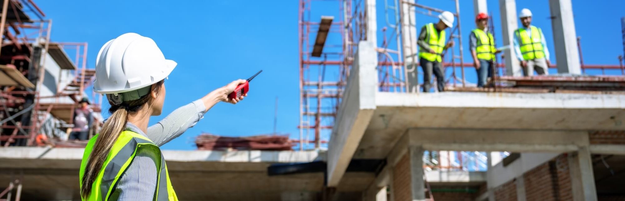 Woman in white hard hat pointing at a construction site