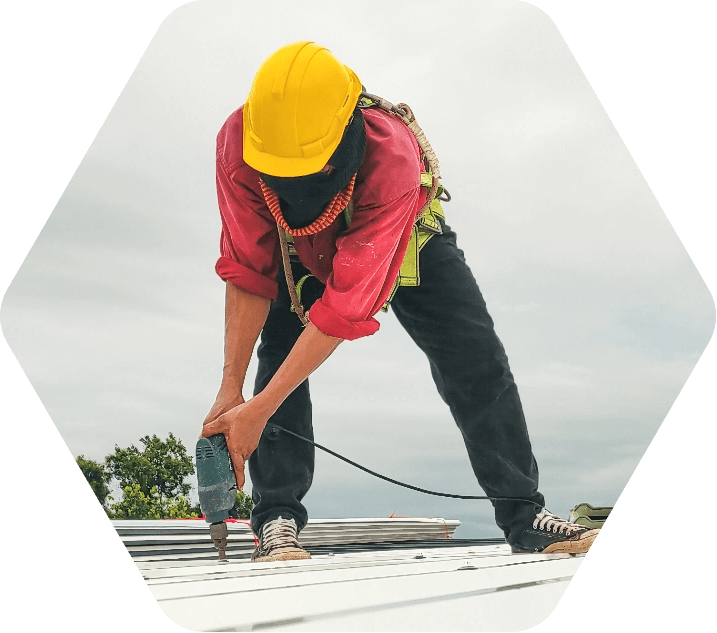 Man in yellow hard hat drilling screws on a roof