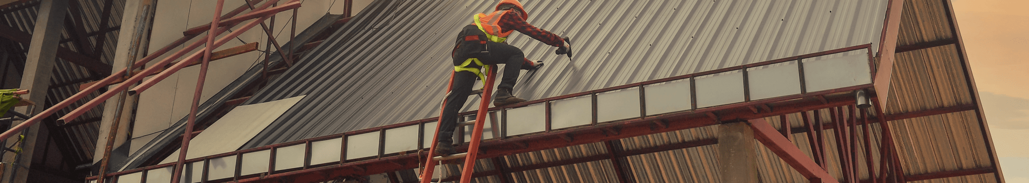 Man on a ladder drilling holes into a metal roof