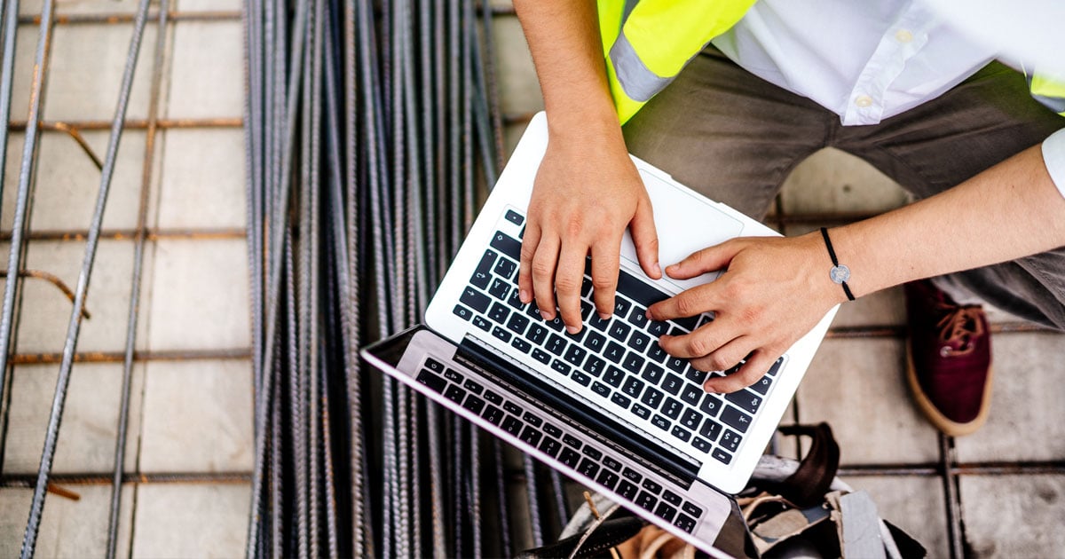 Aerial view of a person's hands typing on a laptop keyboard